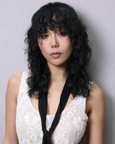 Closeup shot of a model with a curly wolf cut